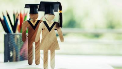 Wooden stick figures with graduation caps on