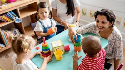 Children and teacher sat playing around a table