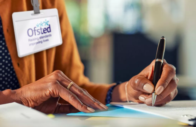 person with Ofsted ID tag writing at desk