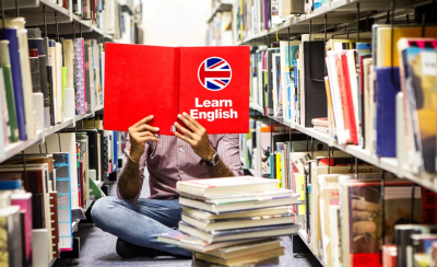 Child sat crossed legged in a library with a red book