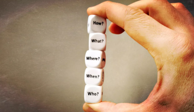 Hands holding dice saying how, what, where, when, who