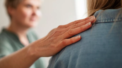 Person comforting another person with hand on shoulder