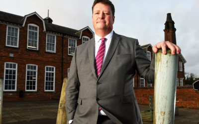 Sir Martyn Oliver stood in front of a school