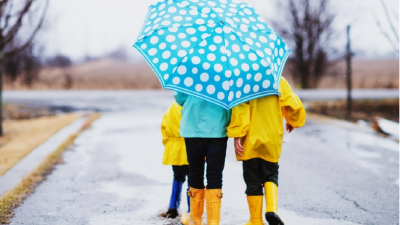Students walking in the rain holding an umbrella above their heads