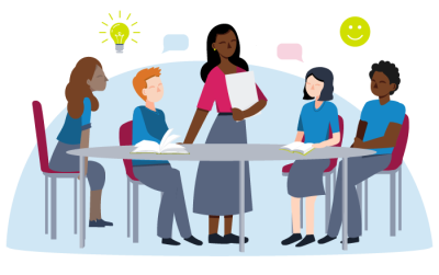 Students at a round desk with female teacher stood in the middle